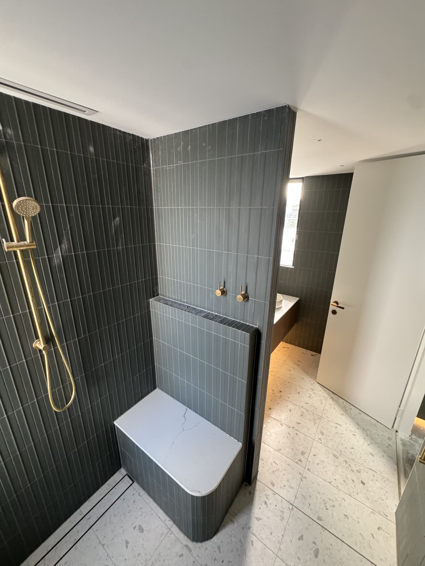 Charcoal vertical tiling in a walk-in shower with tiled bath surround