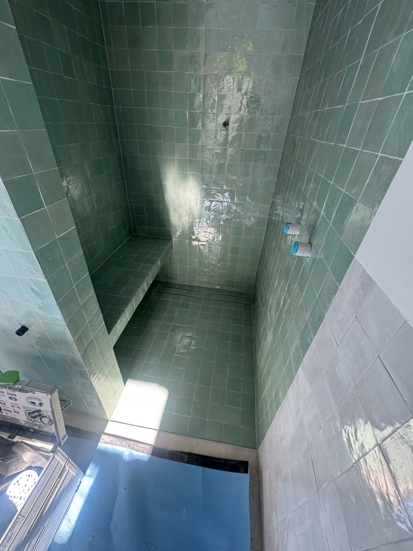 Green zellige-style shower tiling with a tiled bench seat
