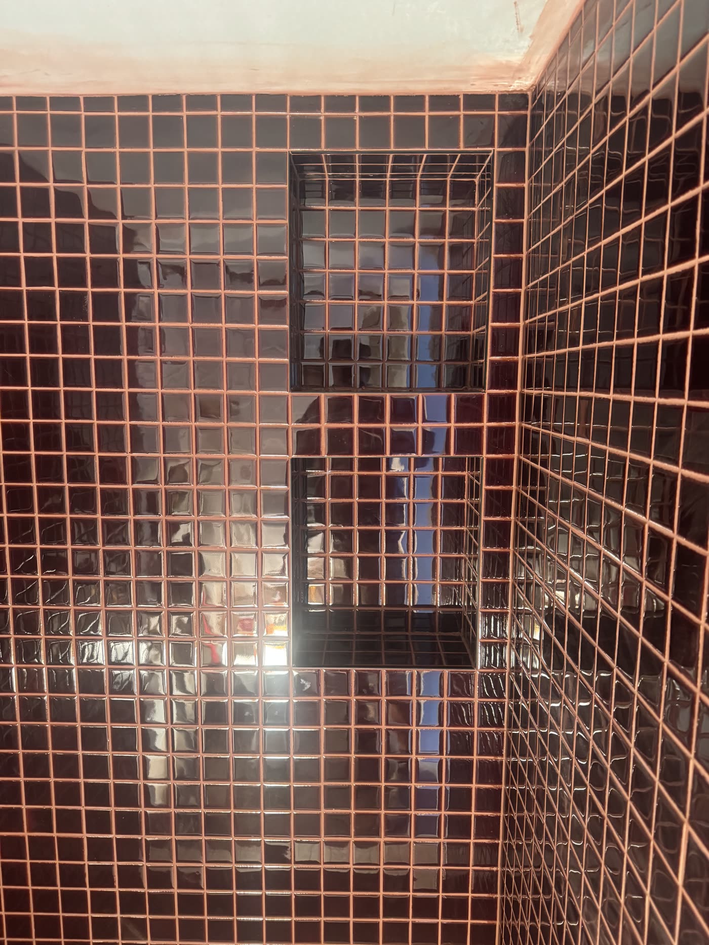Gloss mosaic feature tiling with precise grout lines around a wall niche