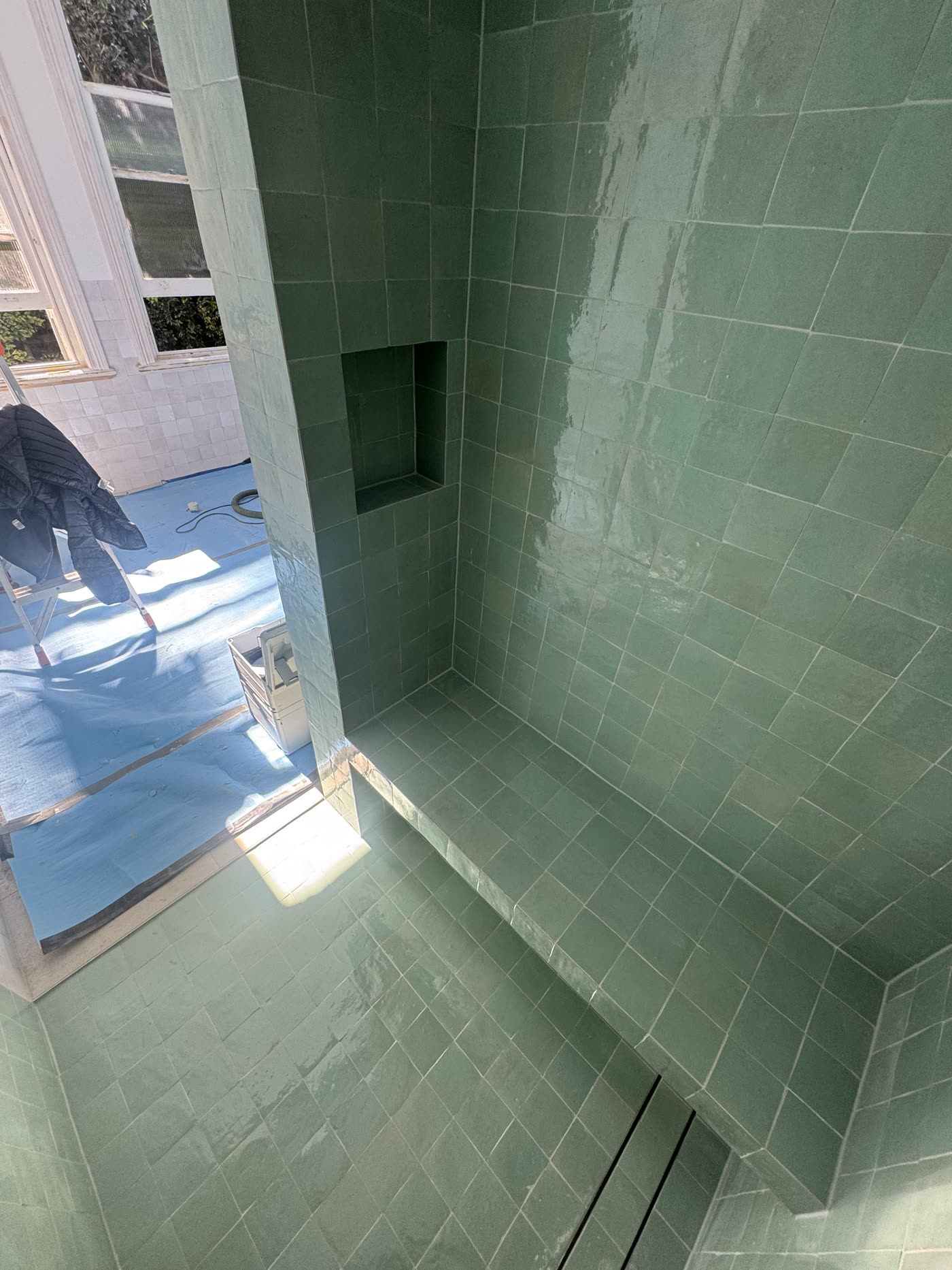 Sage green tiling across shower walls, floor, bench and recessed niche